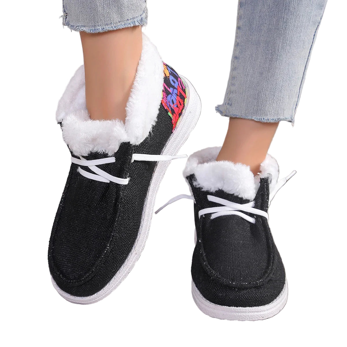 Black slip-on shoes with white fur lining worn by a person on a light wooden floor.